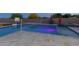 Backyard pool with a volleyball net, basketball hoop, hot tub, and colorful underwater lights at 19777 E Ivy Ln, Queen Creek, AZ 85142