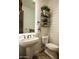 Powder room with shiplap walls, pedestal sink, and decorative shelving offers a charming, functional space at 19777 E Ivy Ln, Queen Creek, AZ 85142