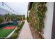 View along the side of the house, showing a walkway bordered by lush foliage that leads to the batting cage at 19777 E Ivy Ln, Queen Creek, AZ 85142
