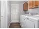 Bright laundry room features white washer and dryer, wooden cabinets, and door to the outside at 2400 E Baseline Ave # 278, Apache Junction, AZ 85119