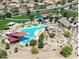Aerial view of a community pool with colorful shade structures, surrounded by lush landscaping and homes at 2486 E Espada Trl, Casa Grande, AZ 85194