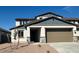Two-story home featuring a two-car garage, stone accents, and a well-manicured yard under a clear blue sky at 25330 W Bowker St, Buckeye, AZ 85326