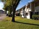 Exterior view of townhomes with a well-maintained lawn, mature trees, and blue sky at 2605 W Rose Ln # B101, Phoenix, AZ 85017
