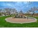 Community playground with slides and climbing structures, surrounded by green grass and mature shade trees at 2737 W Eastman Dr, Anthem, AZ 85086