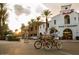 Shopping center with Main Market, outdoor seating, palm trees, and people enjoying the day on bicycles at 3143 N Evergreen St, Buckeye, AZ 85396
