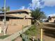 Exterior view of a desert home with a block wall, simple landscaping, and mature trees in a sunny setting at 4231 N 69Th Ln # 1325, Phoenix, AZ 85033