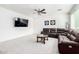 Bright living room with a dark sectional, neutral carpet, a modern ceiling fan, and large windows at 4727 S Watauga Dr, Gilbert, AZ 85297