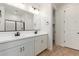 Bright bathroom featuring dual sinks, white cabinets, and a large mirror with modern fixtures at 5359 W Las Palmaritas Dr, Glendale, AZ 85302