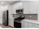 Close-up of a modern kitchen with white cabinets, stainless appliances, and a gray subway tile backsplash at 5401 W Las Palmaritas Dr, Glendale, AZ 85302