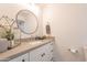 Bright bathroom features a round mirror, light countertop, and white cabinets at 5650 E Presidio Rd, Scottsdale, AZ 85254