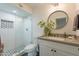 Stylish bathroom with a tiled shower, modern vanity, and decorative round mirror at 5650 E Presidio Rd, Scottsdale, AZ 85254