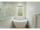 Bright white bathroom with a standalone tub and a window for natural light at 5650 E Presidio Rd, Scottsdale, AZ 85254