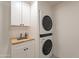 The laundry room has custom cabinets, a sink with butcher block countertop, and stacked washer and dryer at 5650 E Presidio Rd, Scottsdale, AZ 85254