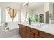 Bright bathroom featuring double sinks, large mirror, and window letting in lots of natural light at 6887 S Teresa Dr, Chandler, AZ 85249
