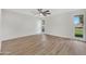 Spacious bedroom featuring wood-look flooring, neutral walls, a ceiling fan, and ample natural light at 9606 W Shasta Dr, Sun City, AZ 85351