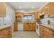 Bright kitchen with white appliances, oak cabinets, and tile floor at 10004 W Desert Forest Cir, Sun City, AZ 85351