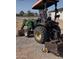 View of a green tractor, parked near the house which is surrounded by white fencing at 11612 S 211Th Ln, Buckeye, AZ 85326