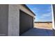 Side view of home featuring black garage door and desert landscaping at 11612 S 211Th Ln, Buckeye, AZ 85326