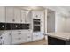 Close-up of kitchen with sleek black backsplash, white cabinets, and stainless steel double ovens at 11612 S 211Th Ln, Buckeye, AZ 85326