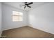 Empty bedroom with neutral carpet, a ceiling fan, and a large window, bathed in natural light at 1280 E Redwood Dr, Chandler, AZ 85286