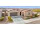 Front exterior showing desert landscaping, two-car garage and front entry at 18059 W Tanglewood Dr, Goodyear, AZ 85338