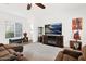 Comfortable living room featuring a large window with blinds, a ceiling fan, and a cozy carpeted area at 18059 W Tanglewood Dr, Goodyear, AZ 85338