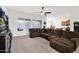 Spacious living room features a large brown corduroy sectional sofa, carpet floors, and large windows at 18059 W Tanglewood Dr, Goodyear, AZ 85338