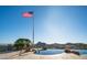 Beautiful infinity pool with an American flag, green trees and blue sky in the background at 3168 S Yaqui Ln, Gold Canyon, AZ 85118