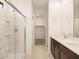 Bright bathroom featuring a glass shower, dual sink vanity, and walk in closet with neutral color palette and tile flooring at 36986 W Prado St, Maricopa, AZ 85138