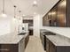 Spacious kitchen featuring dark wood cabinets, granite countertops, and modern stainless steel appliances at 36986 W Prado St, Maricopa, AZ 85138