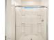 Bathroom featuring a walk-in shower with glass doors, a chrome shower head, and built in shower shelves at 36986 W Prado St, Maricopa, AZ 85138