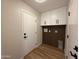 Functional laundry room with white cabinets, wood accent wall, and modern fixtures at 4524 W Larkspur Dr, Glendale, AZ 85304