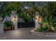 Elegant gated entrance featuring a paver driveway, lush landscaping, and stone pillars with antique sconces, exuding privacy and sophistication at 4900 E Desert Fairways Dr, Paradise Valley, AZ 85253