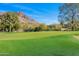 Beautiful golf course view with lush green grass and mountain backdrop on a sunny day at 4900 E Desert Fairways Dr, Paradise Valley, AZ 85253