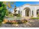 Circular drive with a tiered water fountain in the front of an elegant home with a grand arched entrance at 4900 E Desert Fairways Dr, Paradise Valley, AZ 85253