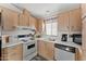 Well-lit kitchen featuring white appliances, wood cabinets, and a window view at 5735 E Mcdowell Rd # 147, Mesa, AZ 85215