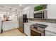 Modern white kitchen with stainless steel appliances, backsplash, and quartz countertops at 6917 E Flossmoor Ave, Mesa, AZ 85208