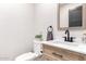 Modern powder room featuring a wood vanity, black hardware, and decorative accents at 7849 W Kristal Way, Glendale, AZ 85308