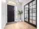 Elegant foyer featuring modern black doors, decorative plant, and sleek hardwood flooring at 7849 W Kristal Way, Glendale, AZ 85308