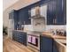 Modern kitchen featuring navy cabinets, stainless steel appliances, and a farmhouse sink at 8923 W Acoma Dr, Peoria, AZ 85381