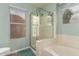 Bright bathroom featuring a standalone glass shower, bathtub, and window at 9859 W Irma Ln, Peoria, AZ 85382