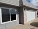 Exterior detail of a home featuring a two-car garage door with updated brick accents and landscaping at 9862 W Comstock Ct, Sun City, AZ 85373