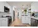 Bright kitchen with white cabinetry, stainless steel appliances, and a stylish bar area with hanging lights and shelves at 1011 E Cavalier Dr, Phoenix, AZ 85014