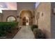 An arched front entrance, desert landscaping, and unique desert themed decor invites guests to enter the home at 10322 E Breathless Ave, Gold Canyon, AZ 85118