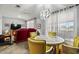 Cozy dining area showcasing a round table with glass top, plush yellow chairs, and bright natural lighting at 10453 W White Mountain Rd, Sun City, AZ 85351