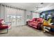 Comfortable living room featuring a plush red sofa, neutral carpet, and abundant natural light at 10453 W White Mountain Rd, Sun City, AZ 85351