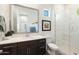 Bright bathroom features a dark vanity, large mirror, framed art, and white tiled shower with glass doors at 12519 W Oyer Ln, Peoria, AZ 85383