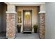 Inviting front door framed by stone pillars and planters, complemented by a charming yellow wreath at 12519 W Oyer Ln, Peoria, AZ 85383