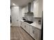 Modern kitchen featuring white cabinetry, subway tile backsplash, stainless steel range hood, and wood-look flooring at 13342 W Lariat Ln, Peoria, AZ 85383