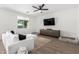 Bright and open living room featuring a white sectional sofa, a modern ceiling fan, and a large TV at 13342 W Lariat Ln, Peoria, AZ 85383